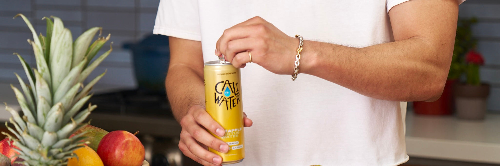Man opening a can of Caliwater Pineapple Cactus Water in a kitchen