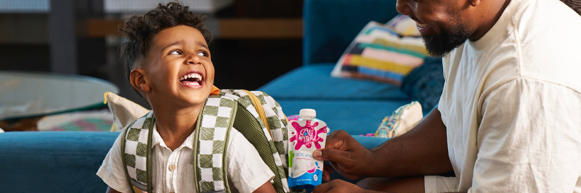 A dad putting a Caliwater Kids Pouch in his son's backpack