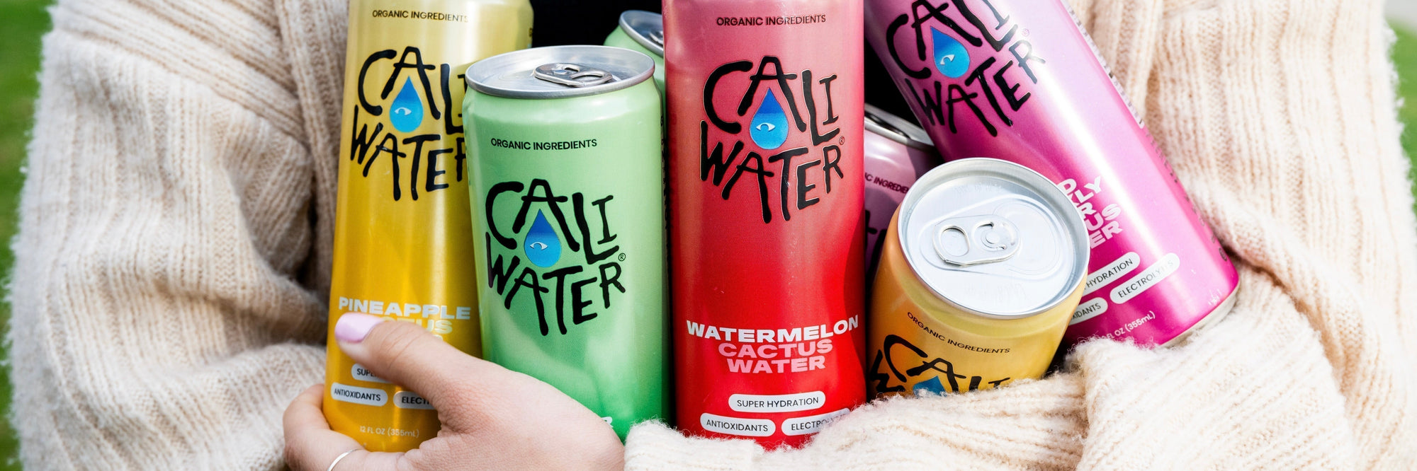 Woman holding several cans of Caliwater Cactus Water